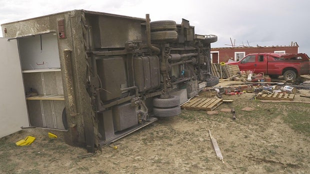 A dramatic image showing the aftermath of the Colorado tornado, with scattered debris and storm clouds overhead.